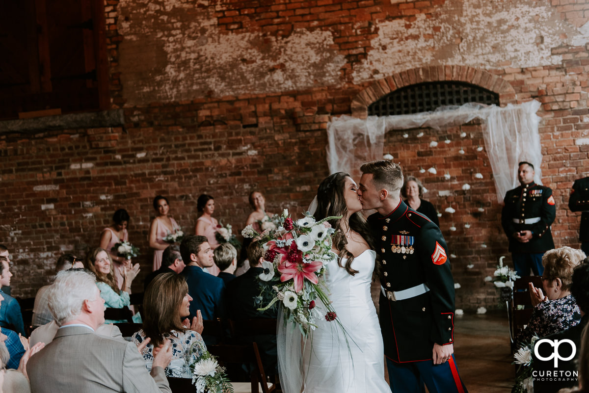 Bride and groom kissing while coming back up the aisle.