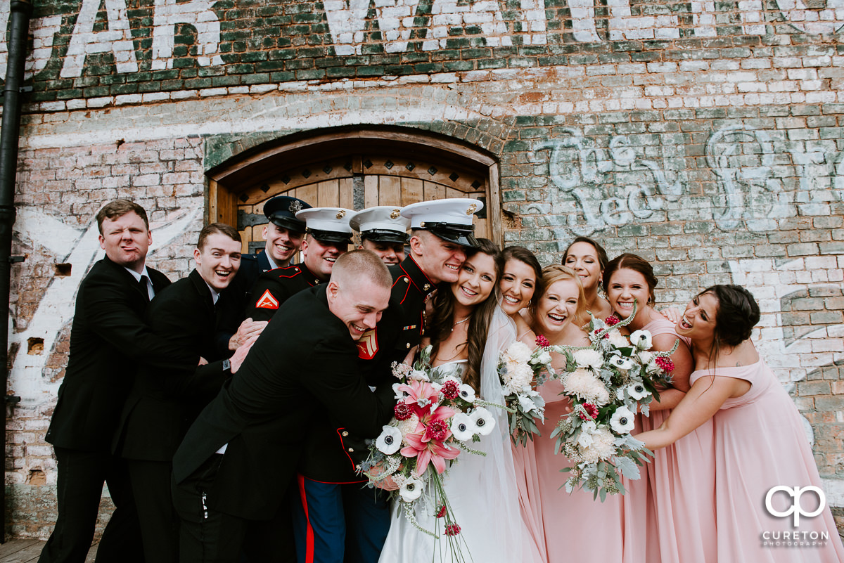 Wedding party hugging the bride.