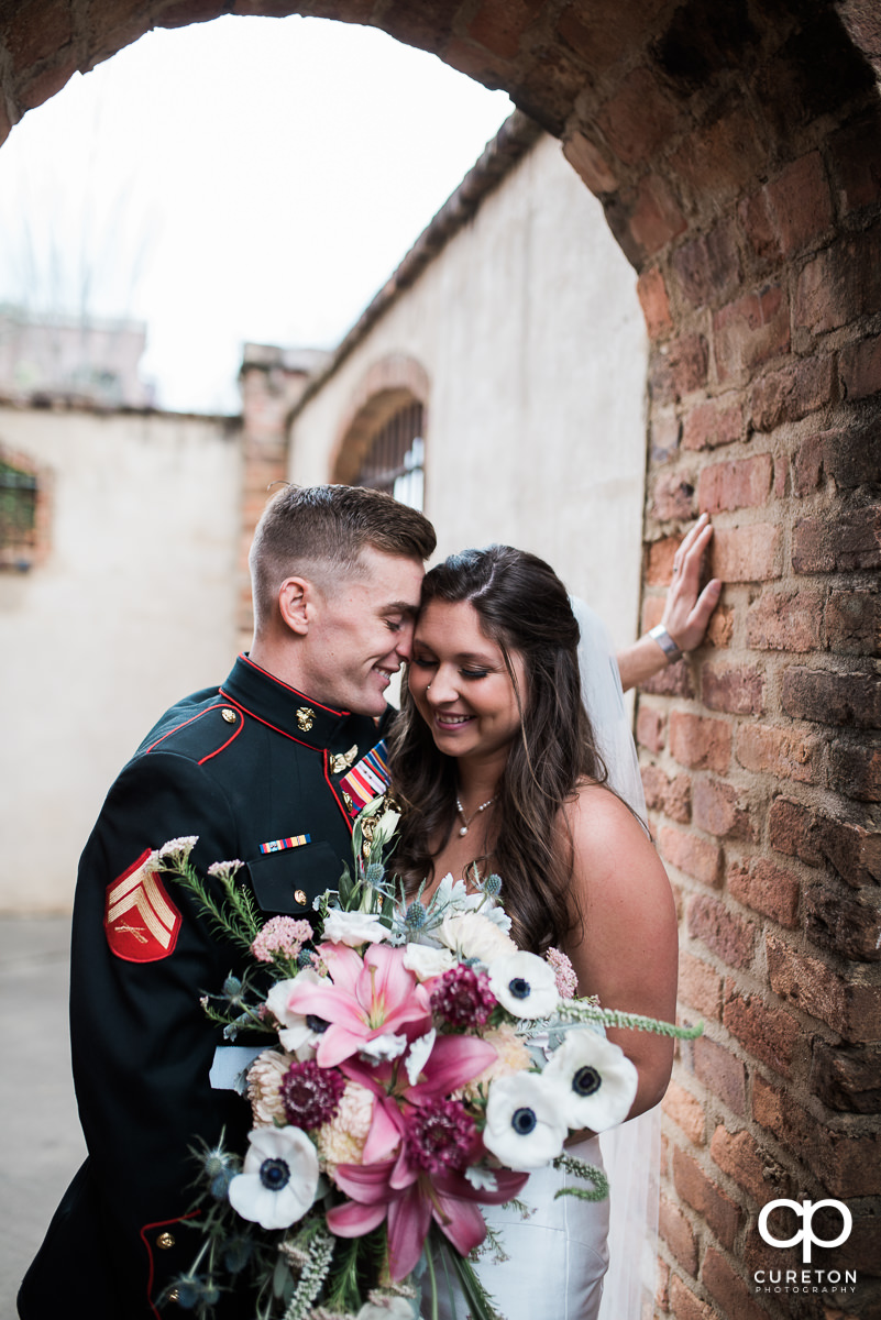 Bride and groom laughing in an archway on their wedding day.