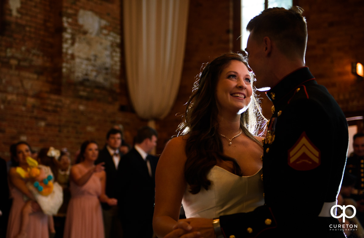 Bride smiling at her groom sharing a first dance at the wedding reception.