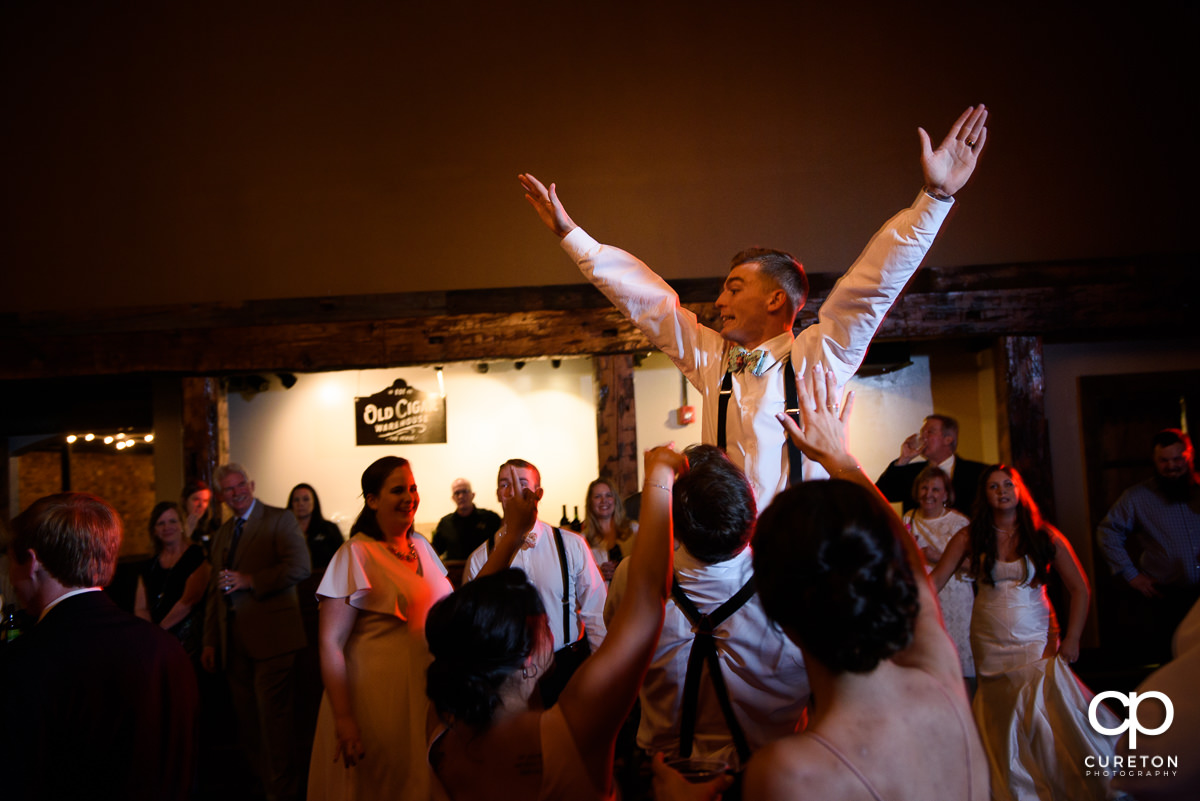 Groom being lifted on the dance floor.