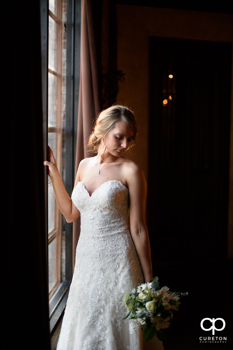Bride holding her bouquet down while standing in perfect window light.
