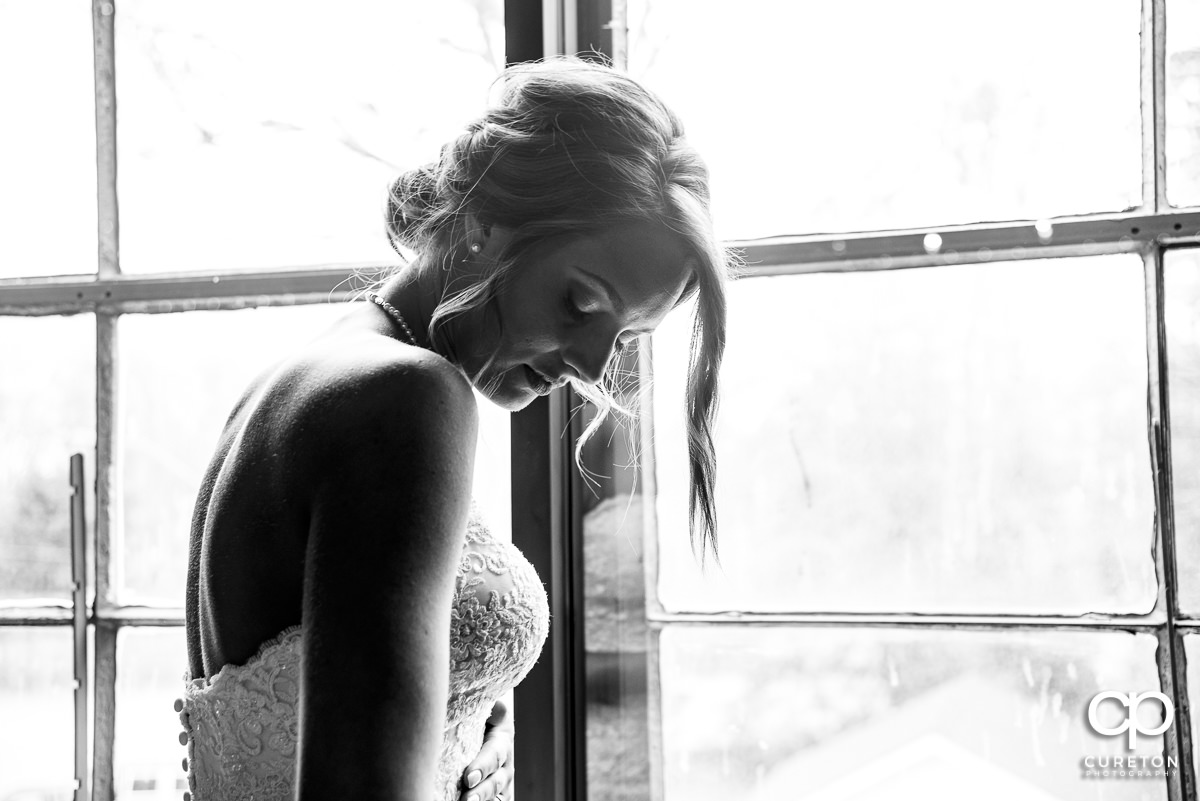 Bride standing in window light.