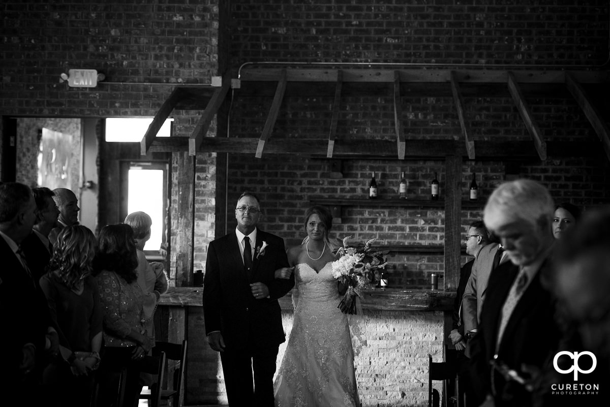 Bride walking down the aisle with her dad crying.