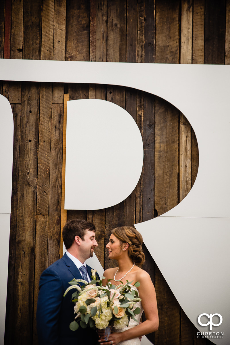 Bride and groom standing underneath a giant letter R.
