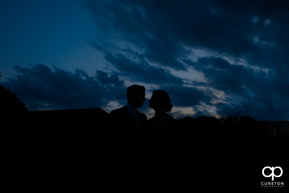 Bride and groom silhouette with deep blue sky before their wedding at Revel Event Center in Greenville,SC.