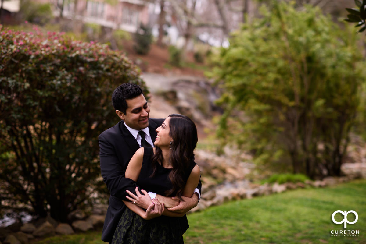 Engaged couple smiling at each other at their engagement session at The Rock Quarry Garden and Cleveland Park in Greenville,SC.