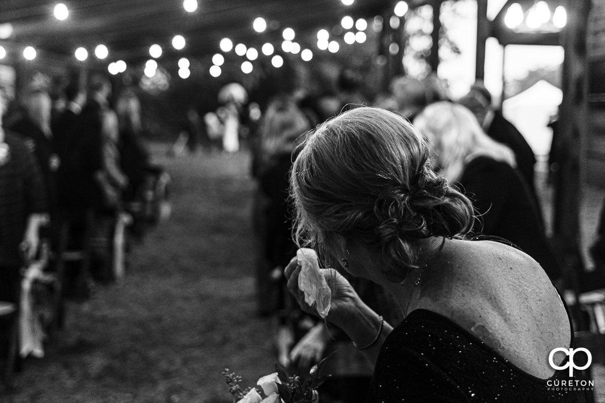 Mother of the bride tearing up as her daughter walks down the aisle.