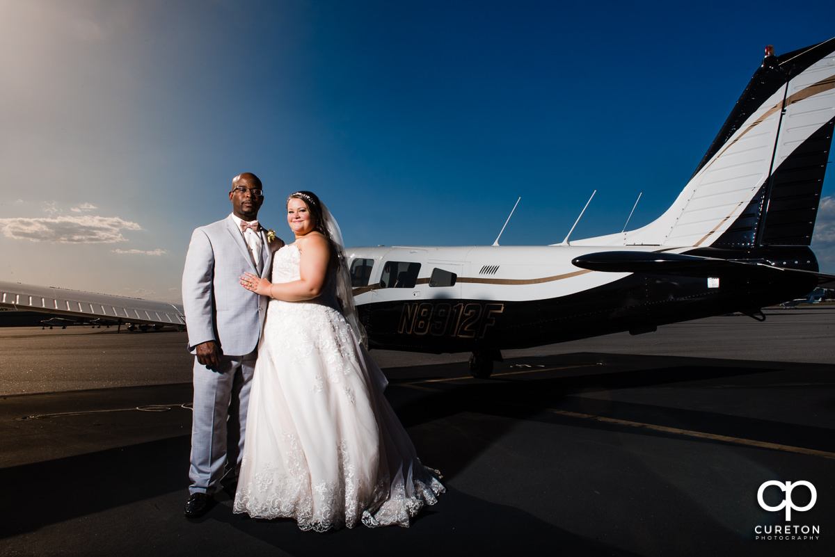 Newly married couple standing beside and airplane at the downtown airport in Greenville,SC.
