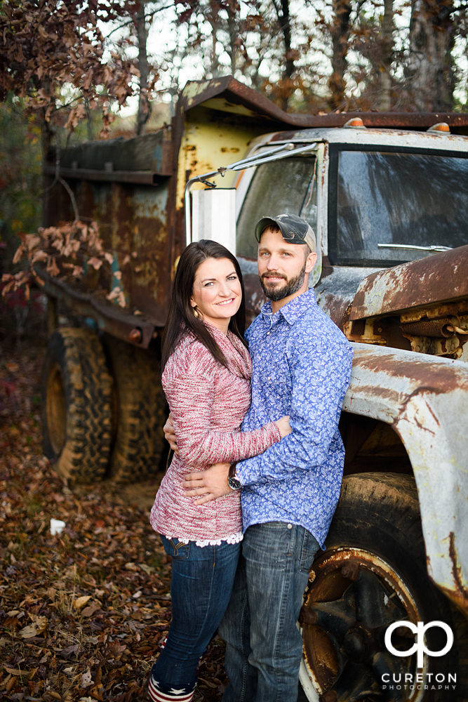 Engaged couple standing near an old rusted truck during their Blue Ridge engagement session.