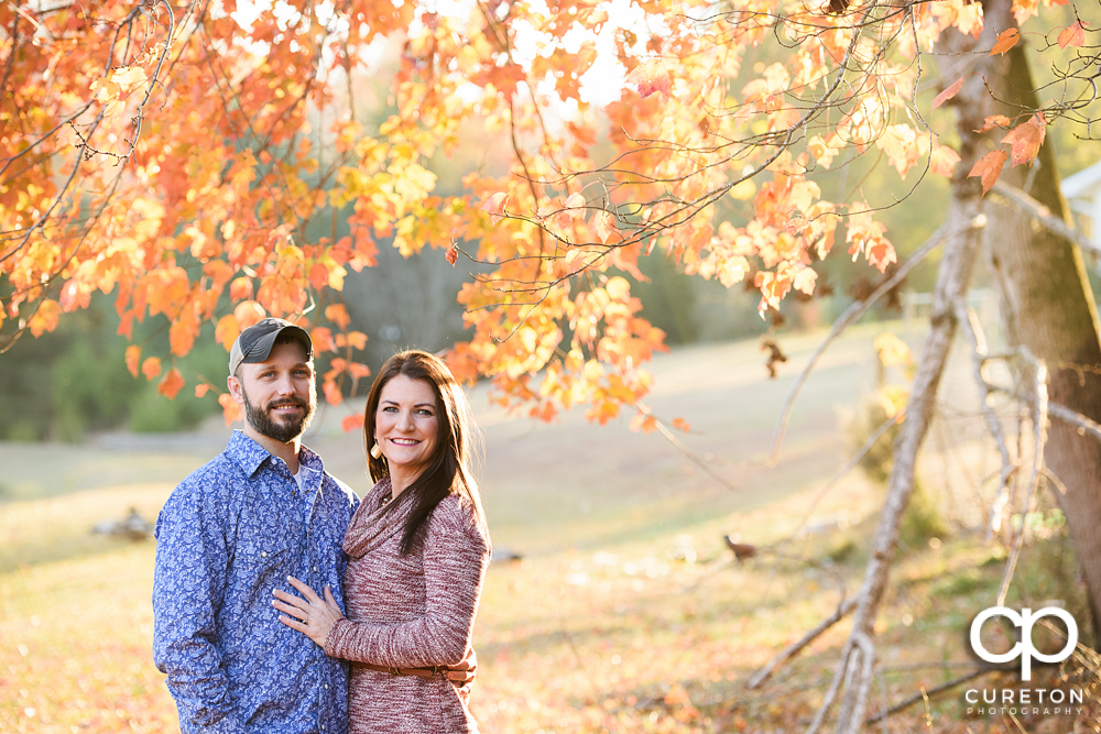 Engaged couple with fall leaves in the background.