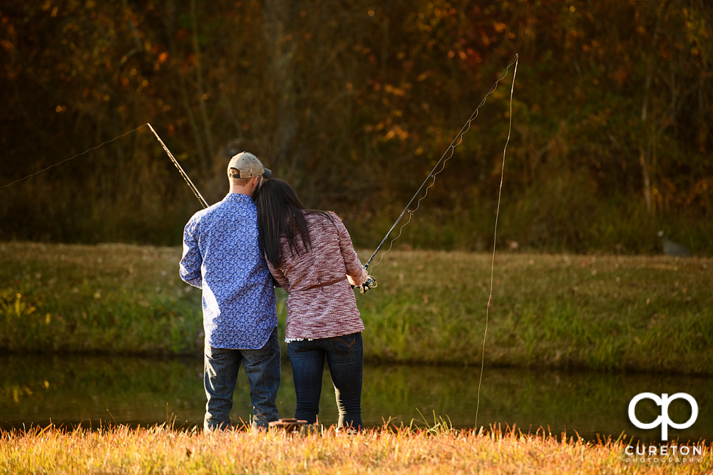 Engaged couple fishing in a pond in Blue Ridge during their engagement session.