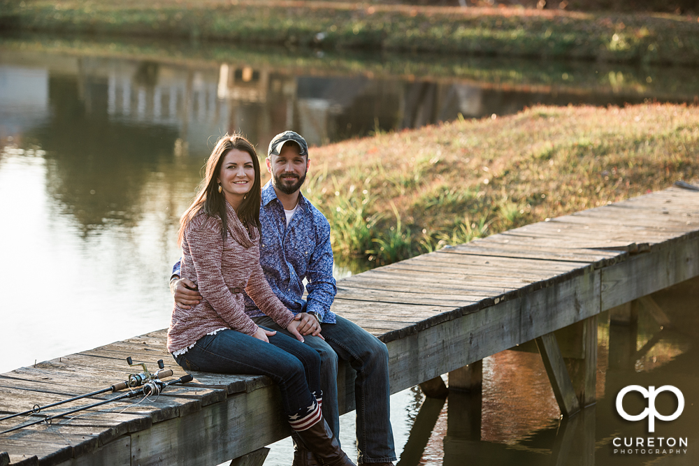 Future bride and groom sitting on a dock.