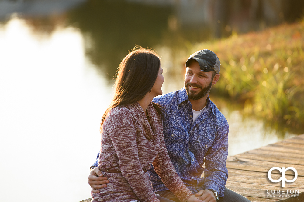 Engaged couple looking at each other on a dock.