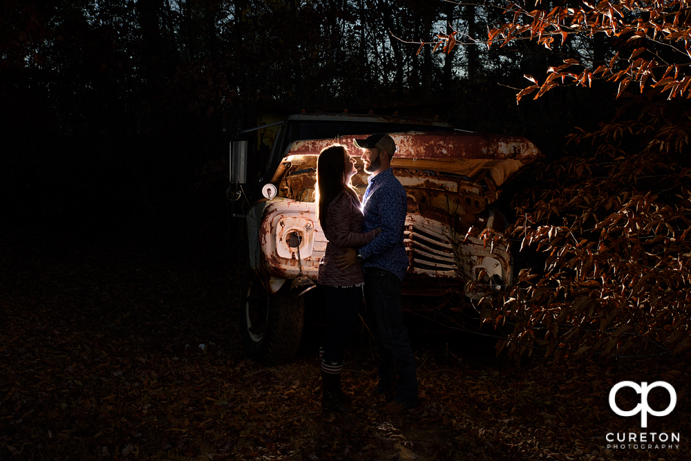 Engaged couple near a rusted truck.