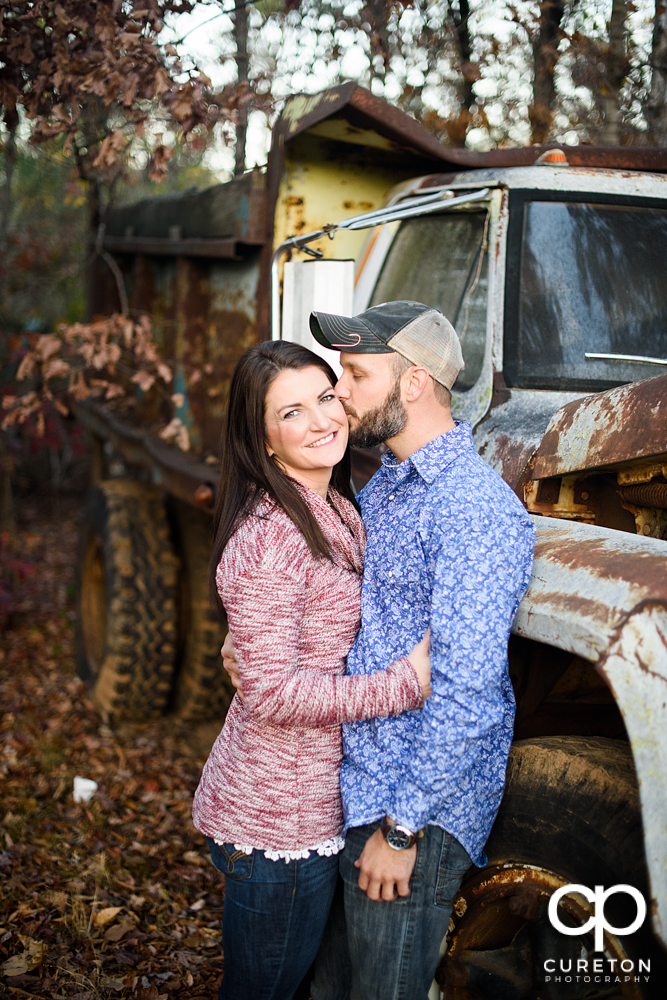 Man kissing his fiancee on the cheek.