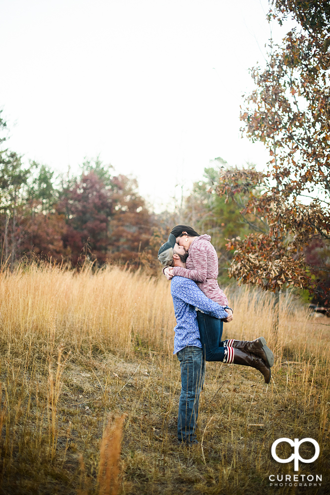 Man lifting his fiancee into his arms.