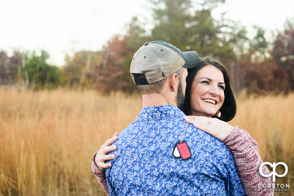 Woman smiling holding her fiancees military dog tags.