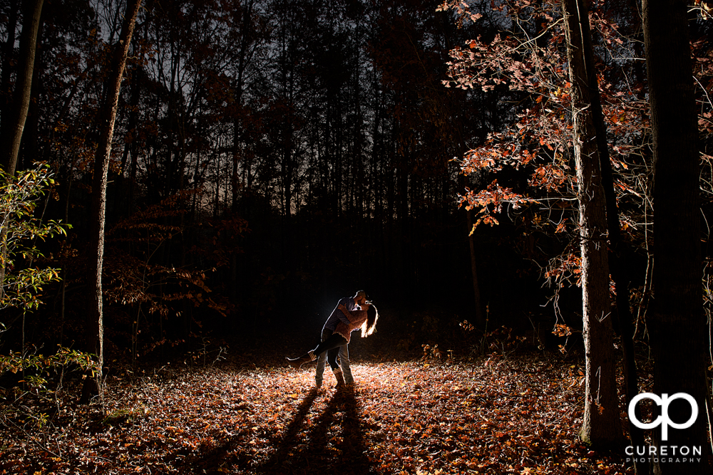 Engaged couple dipping in the forest during their fall Blue Ridge engagement session.