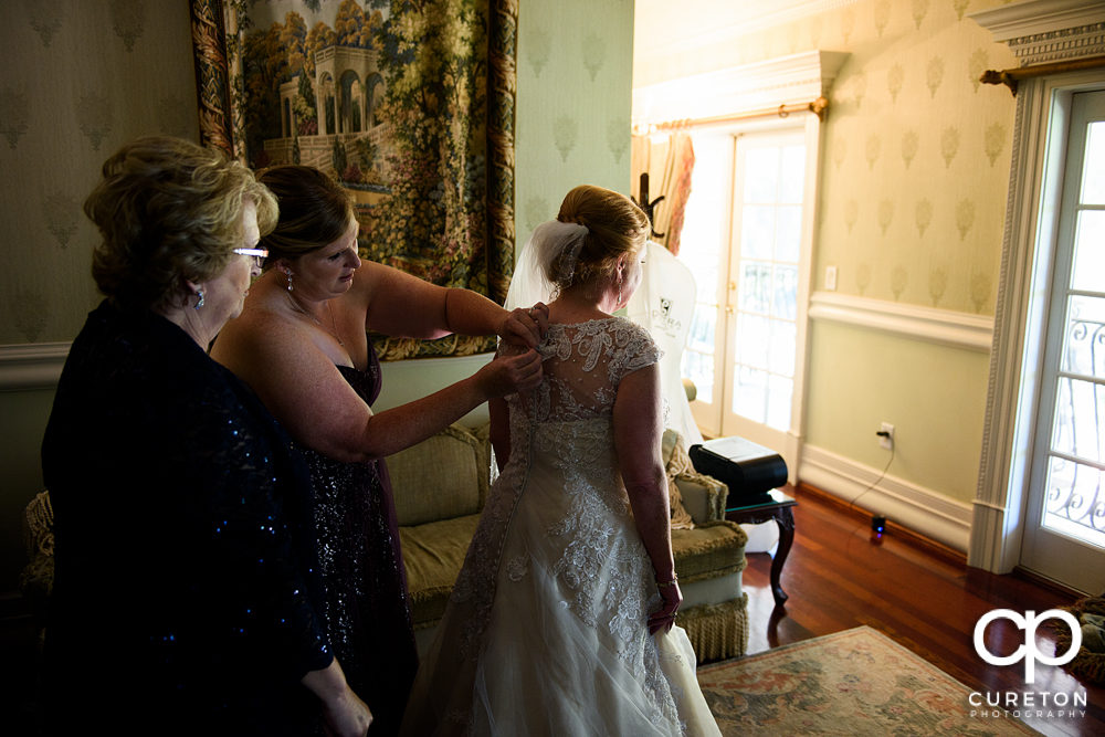 The bride being helped into her dress in the bridal suite of the Ryan Nicholas Inn.