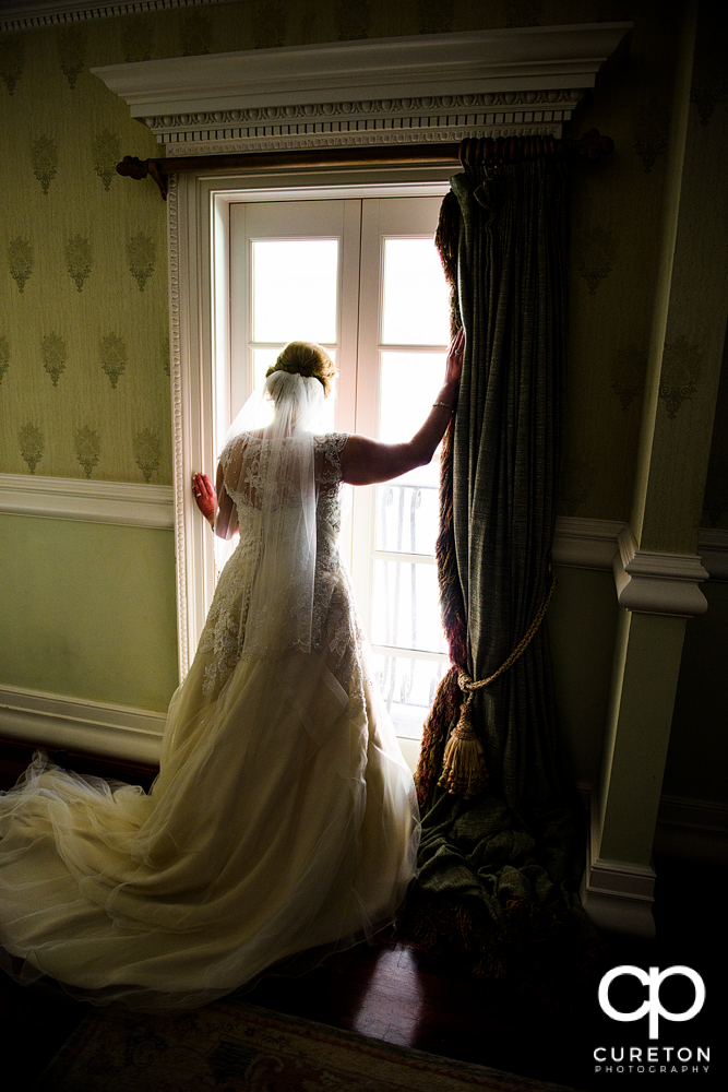 The bride looking out the window of the bridal suite at the Ryan Nicholas Inn.