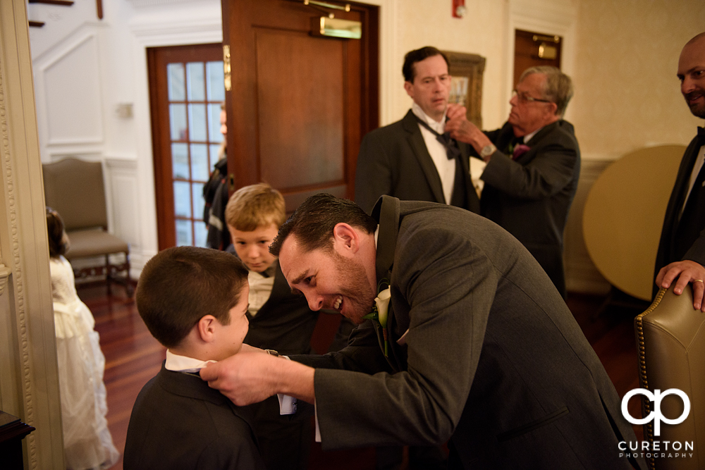 The groom helping his son with the tie.