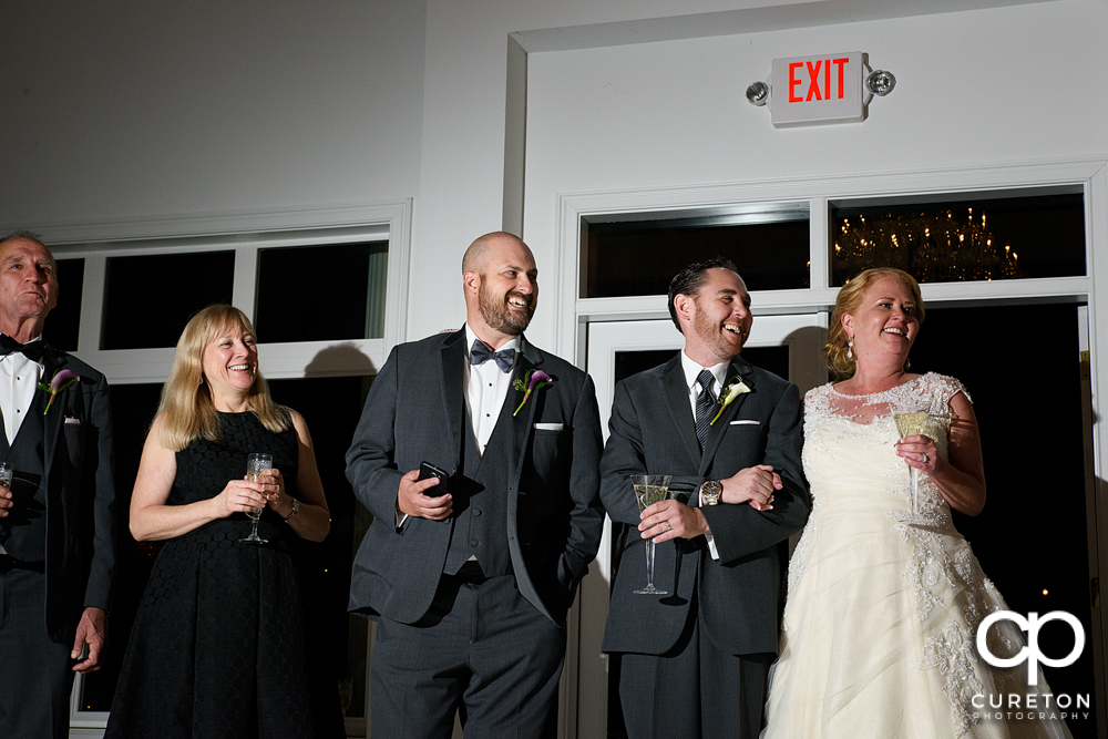 The bride and groom listen as the maid of honor and best man give a toast