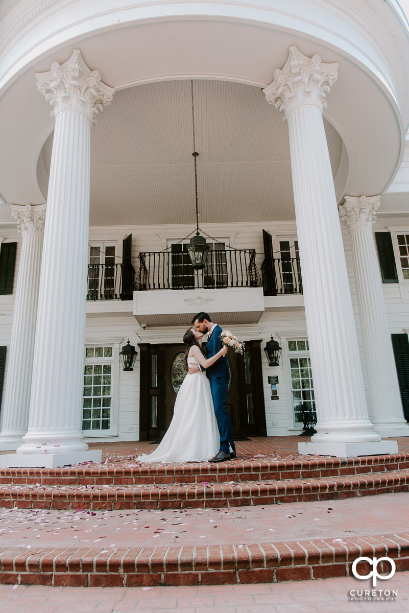 Bride and groom kissing on the porch of the Ryan Nicholas Inn.