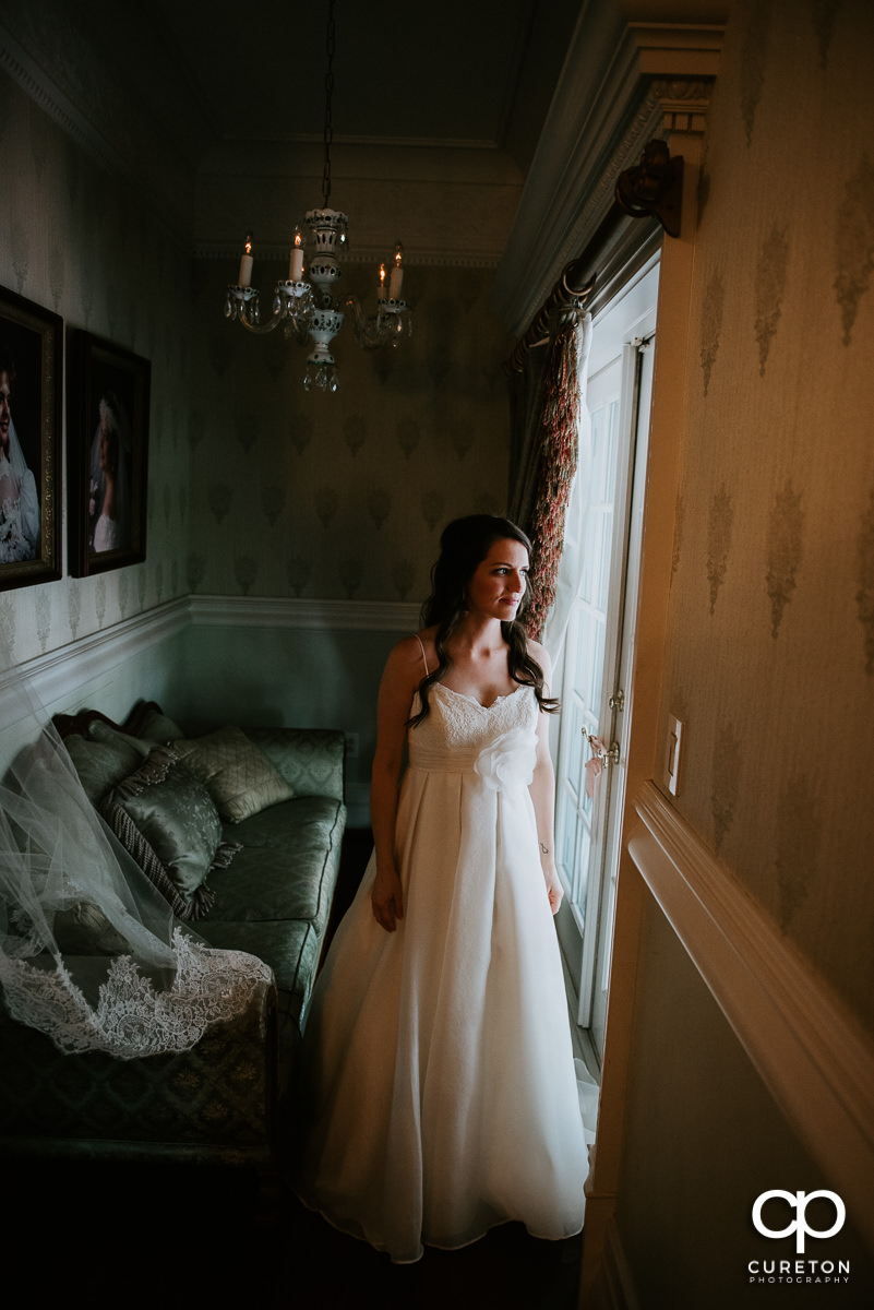 Bride standing in window light in the bridal suite in the Ryan Nicholas Inn before her wedding.
