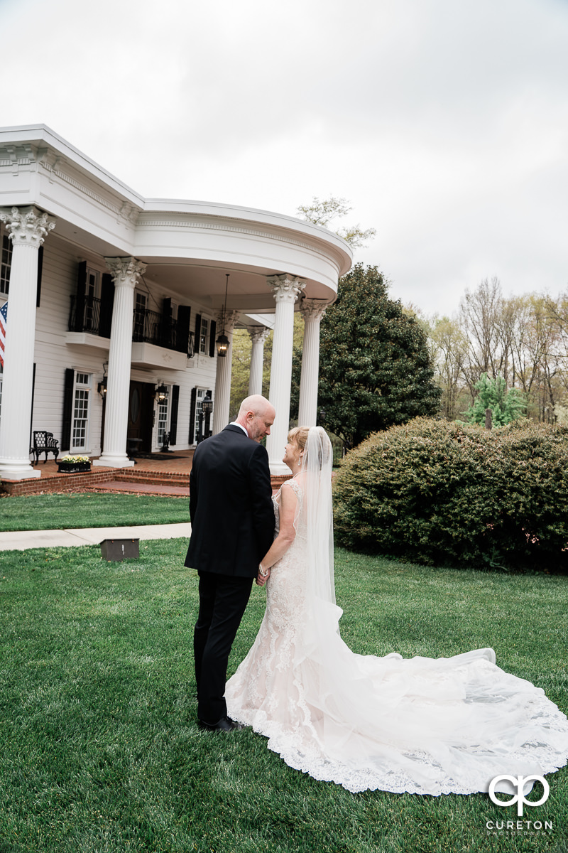 Bride and groom in front of a Southern style mansion.