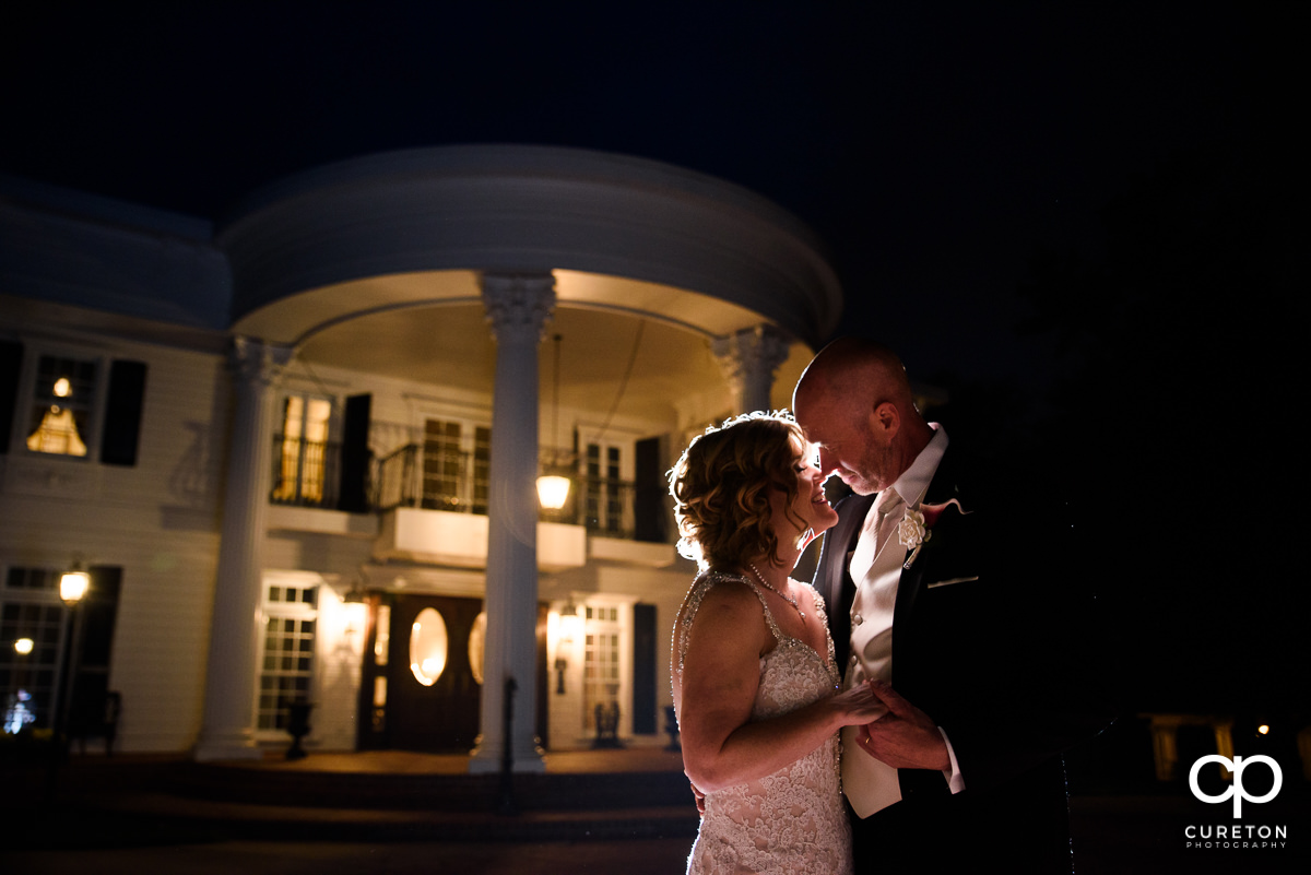 Bride and groom kissing at night in front of the mansion during their Ryan Nicholas Inn wedding in Mauldin,SC.