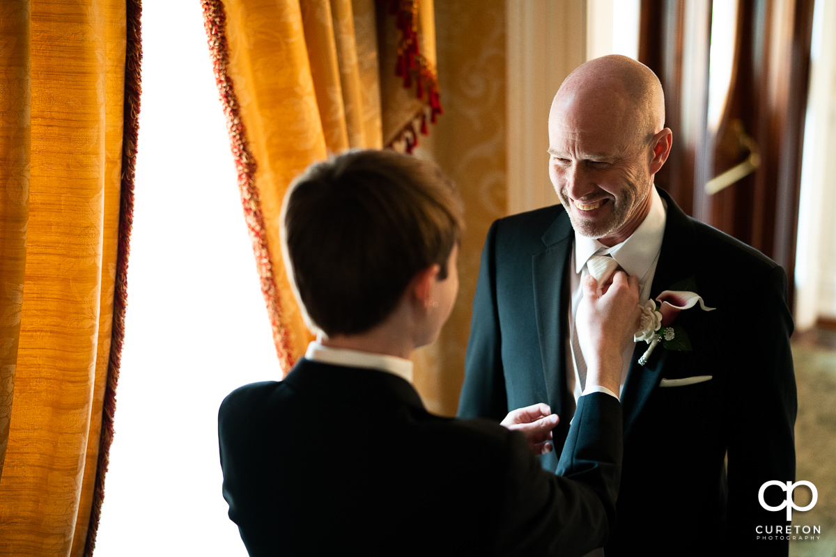 Groom's son helping him with his tie.