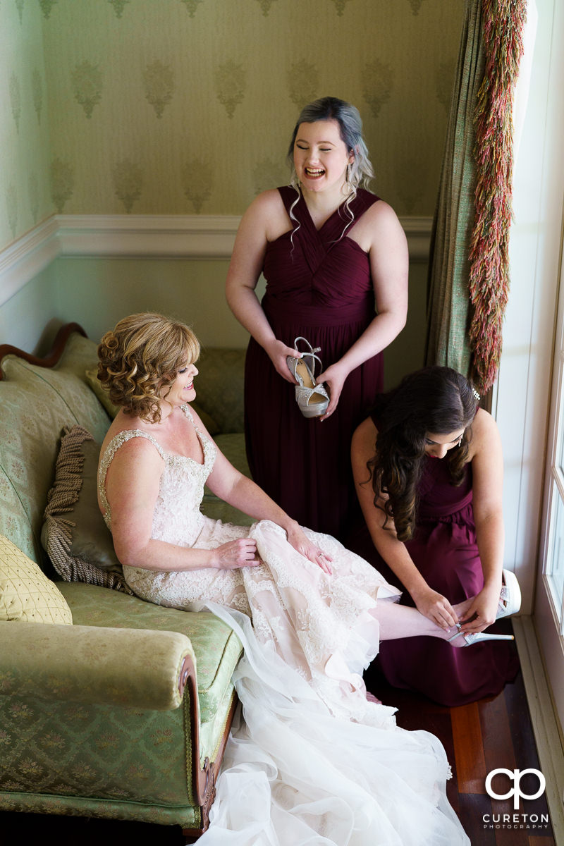 Bridesmaids putting on the bride's shoes.