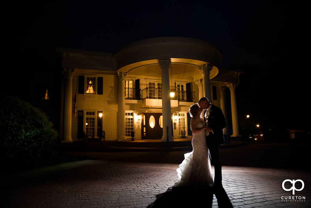 Bride and groom kissing in front of the Southern Plantation style house after their wedding at Ryan Nicholas Inn in Greenville,SC.