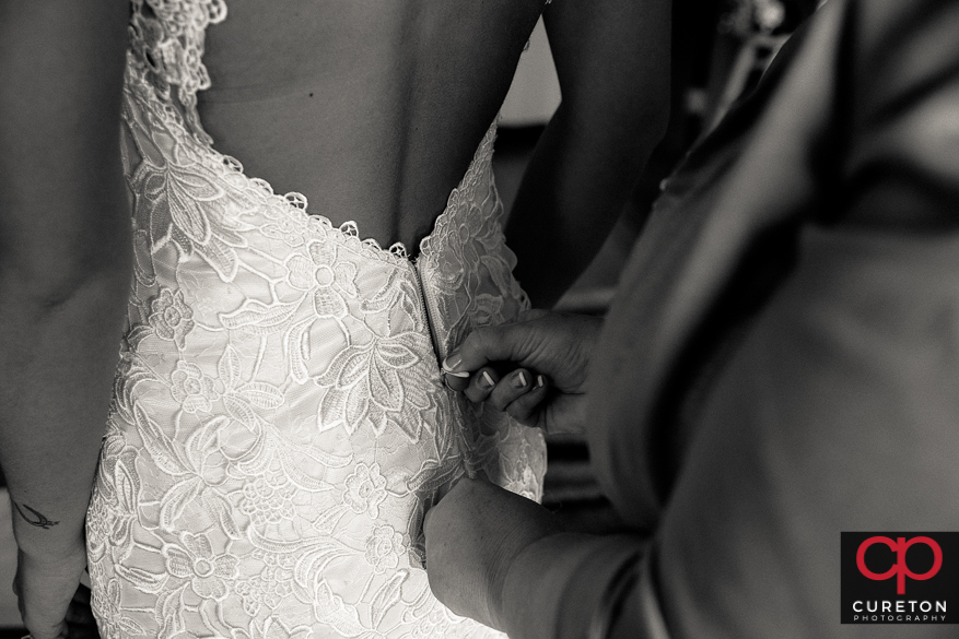 Bride's mom zipping up her dress.