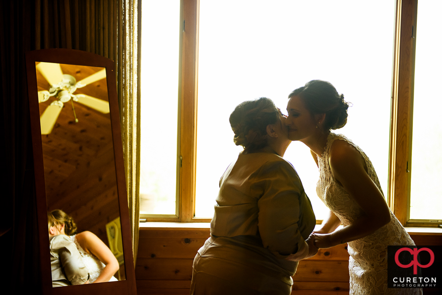 Mother of the bride kissing her on the cheek.