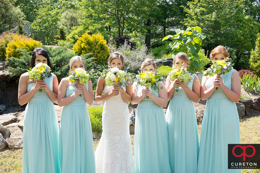 Bride and bridesmaids holding thier flowers up.