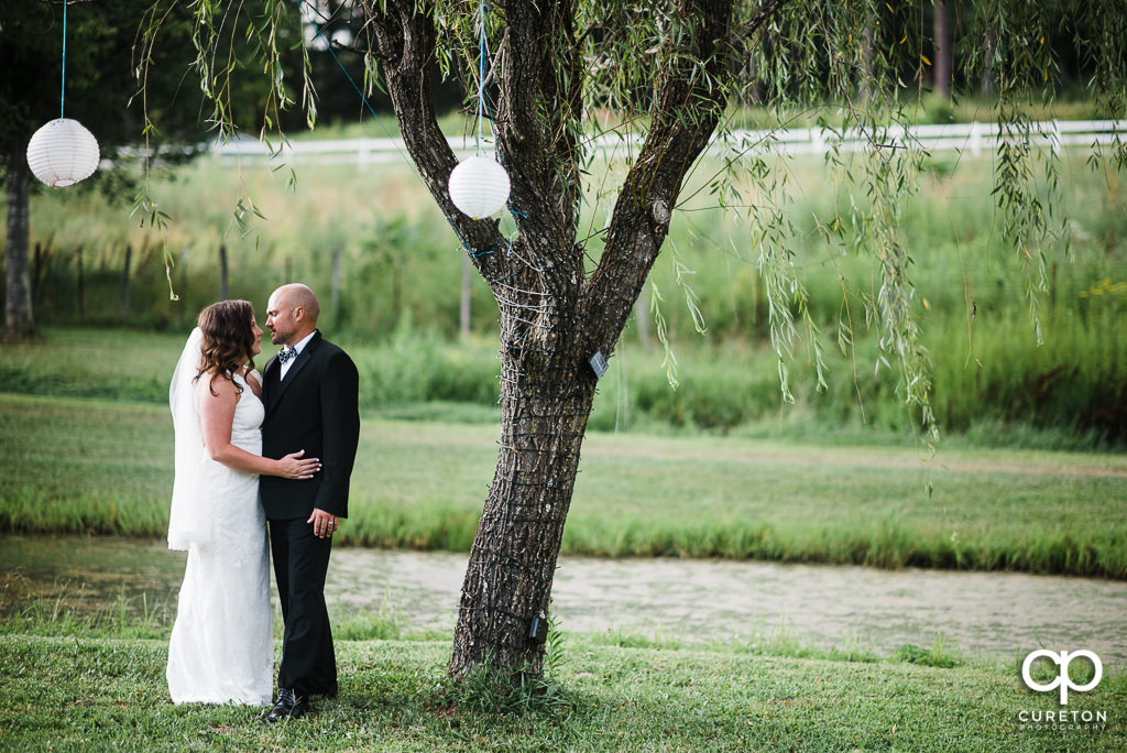 Bride and Groom standing by a tree at South Wind Ranch.