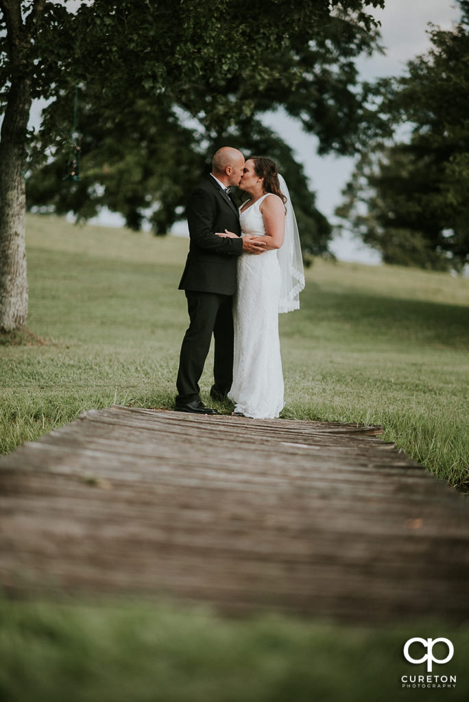 Bride and groom kissing on a dock at South Wind Ranch.