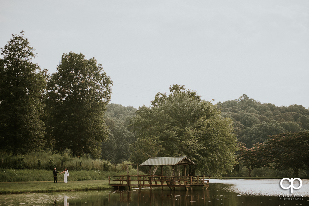 Bride and Groom walking by the lake at South Wind Ranch in Travelers Rest SC.