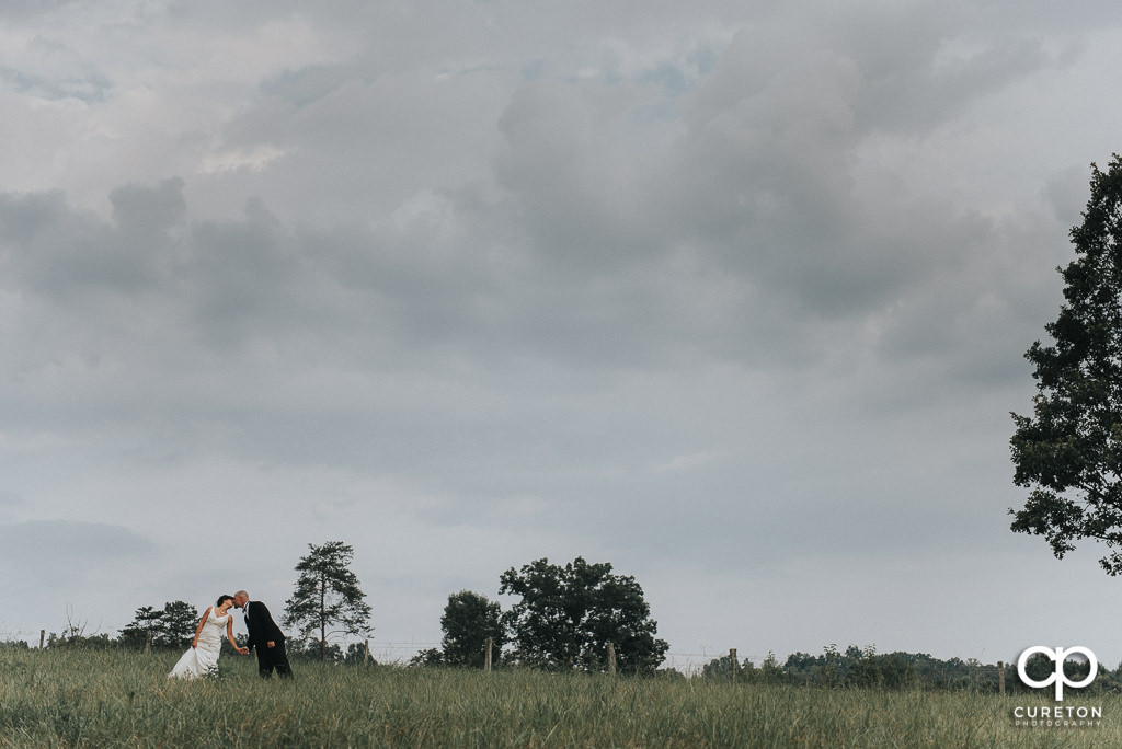 Bride and groom kissing in a field at South Wind Ranch.