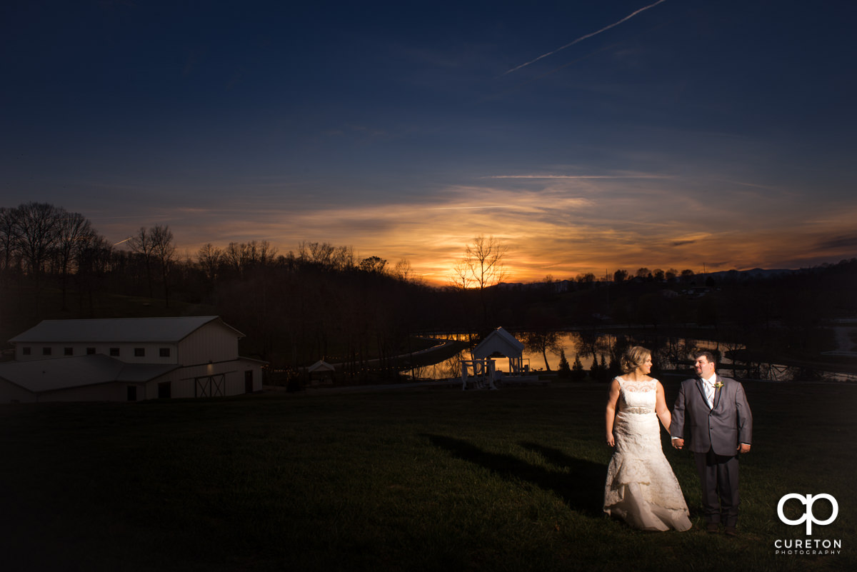 Bride and groom standing in a field at sunset during their South Wind Ranch wedding in Travelers Rest,SC.
