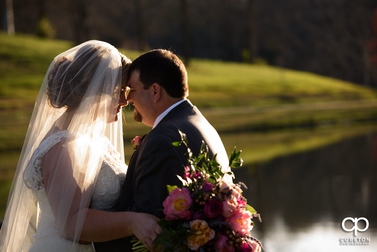 Bride and groom snuggling by the lake during their South Wind Ranch wedding in Travelers Rest,SC.