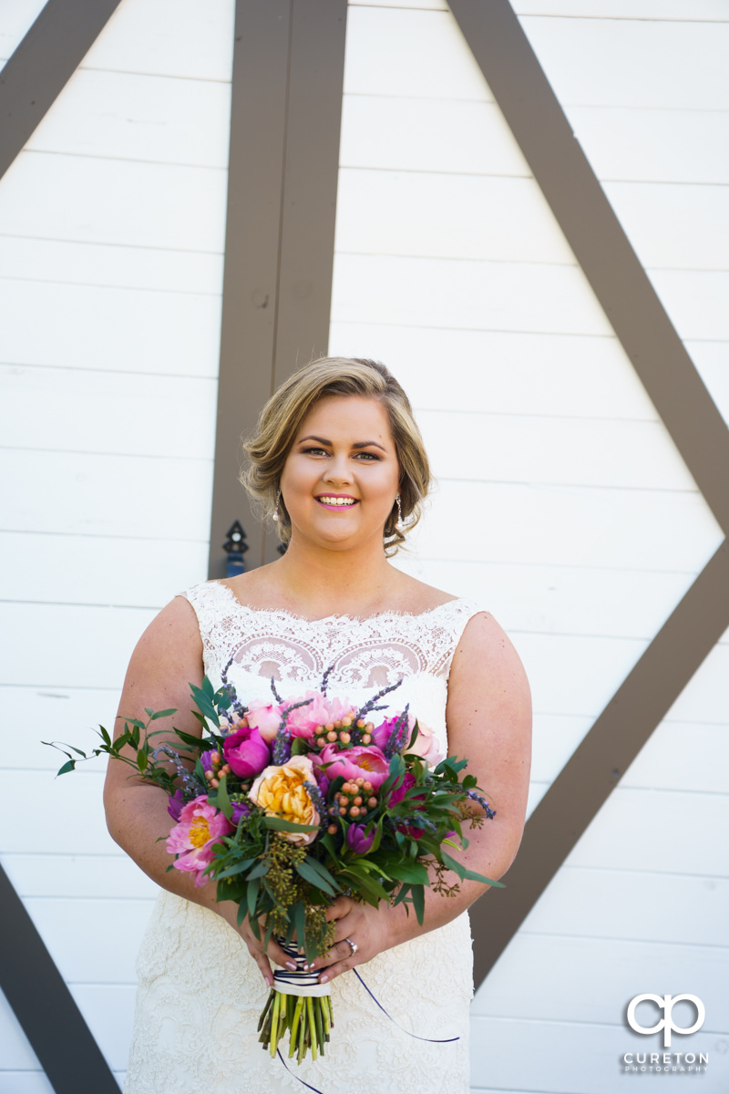 Bride holding her flowers in front of the barn doors at South Wind Ranch.