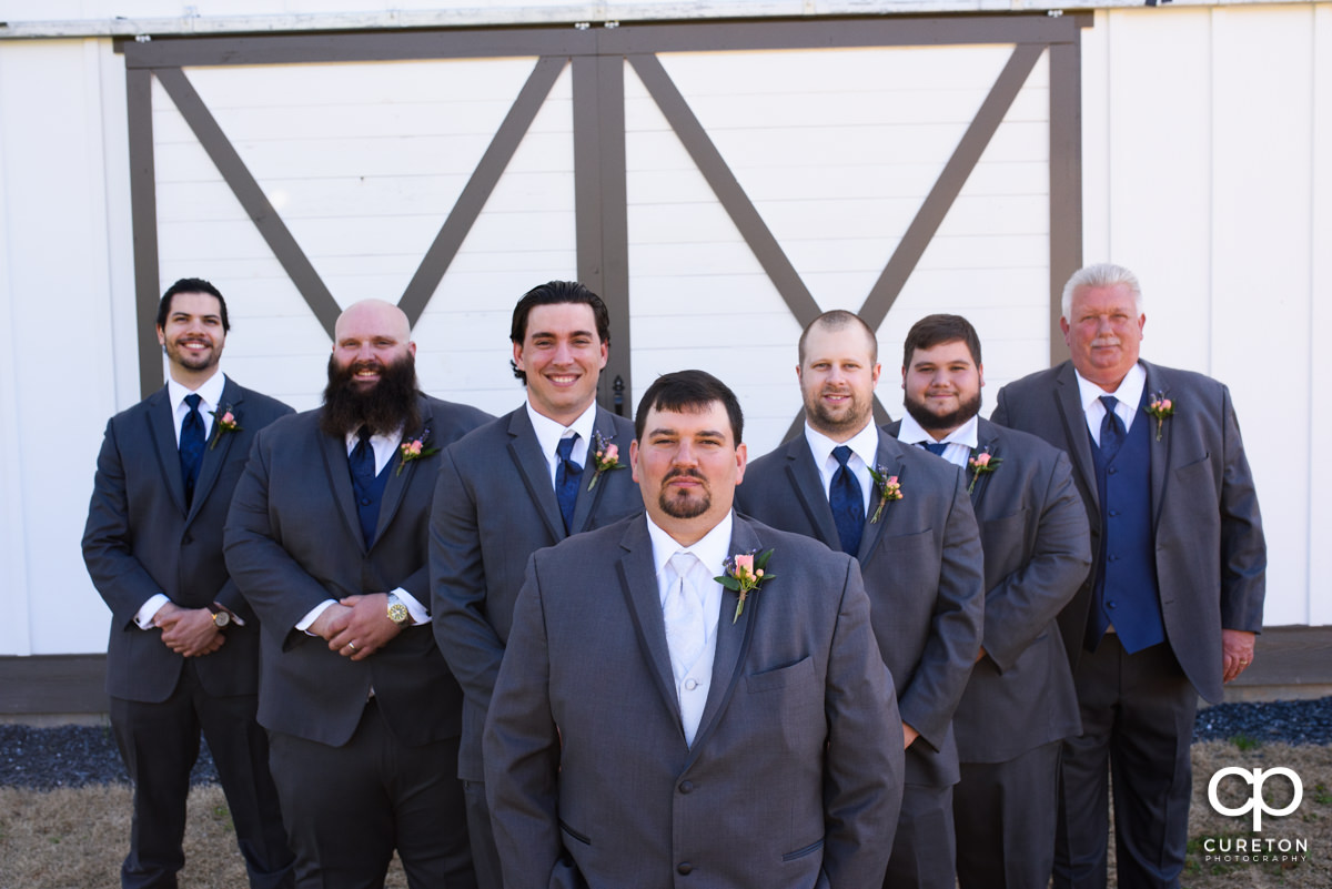 Groom and groomsmen standing in front of a barn door at South Wind Ranch.