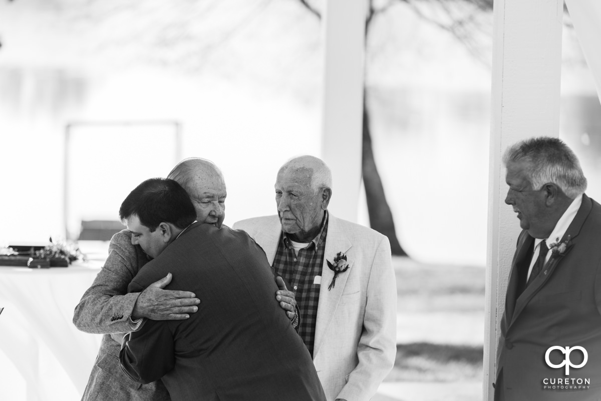 Groom hugging his grandpa at the wedding ceremony.