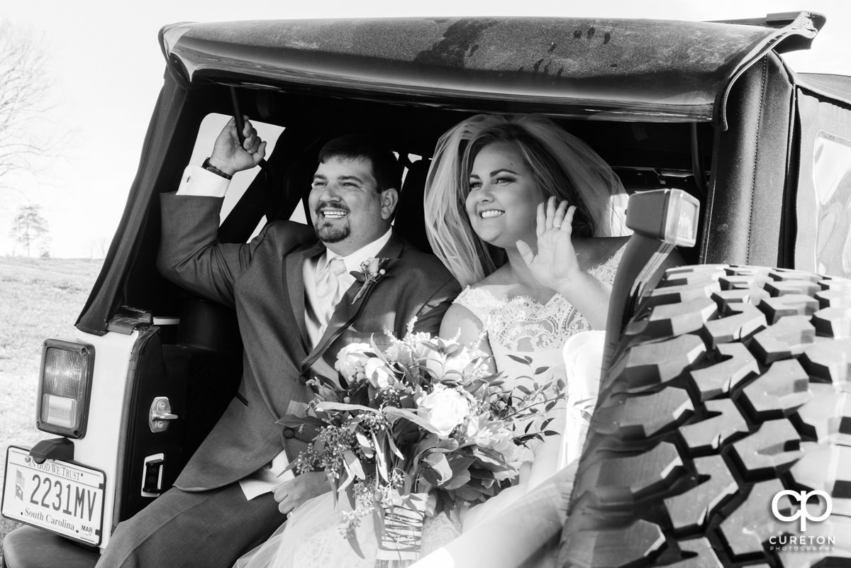 Bride and groom leaving the ceremony in the back of a Jeep.