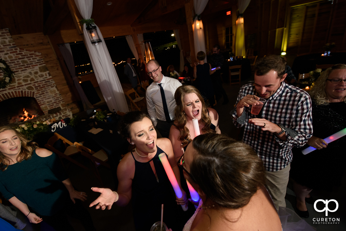 Wedding guests dancing at the reception while holding glow sticks.