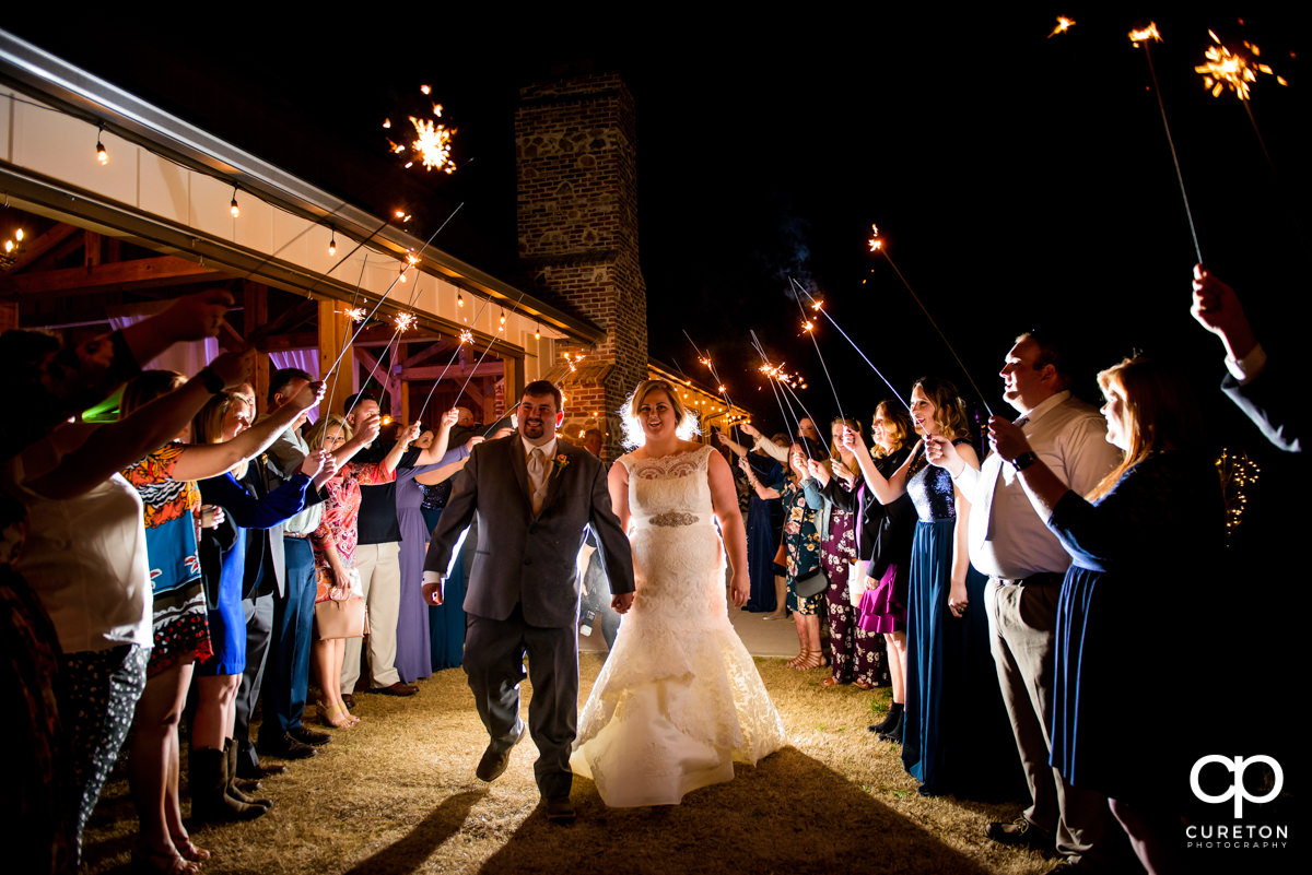 Bride and groom making a grand exit through sparklers at their South Wind Ranch wedding in Travelers Rest,SC.