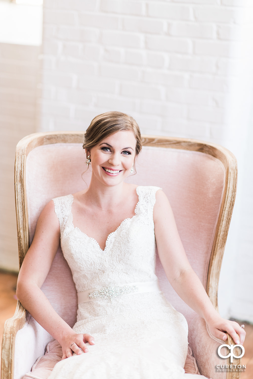 Bride sitting in a pink chair,